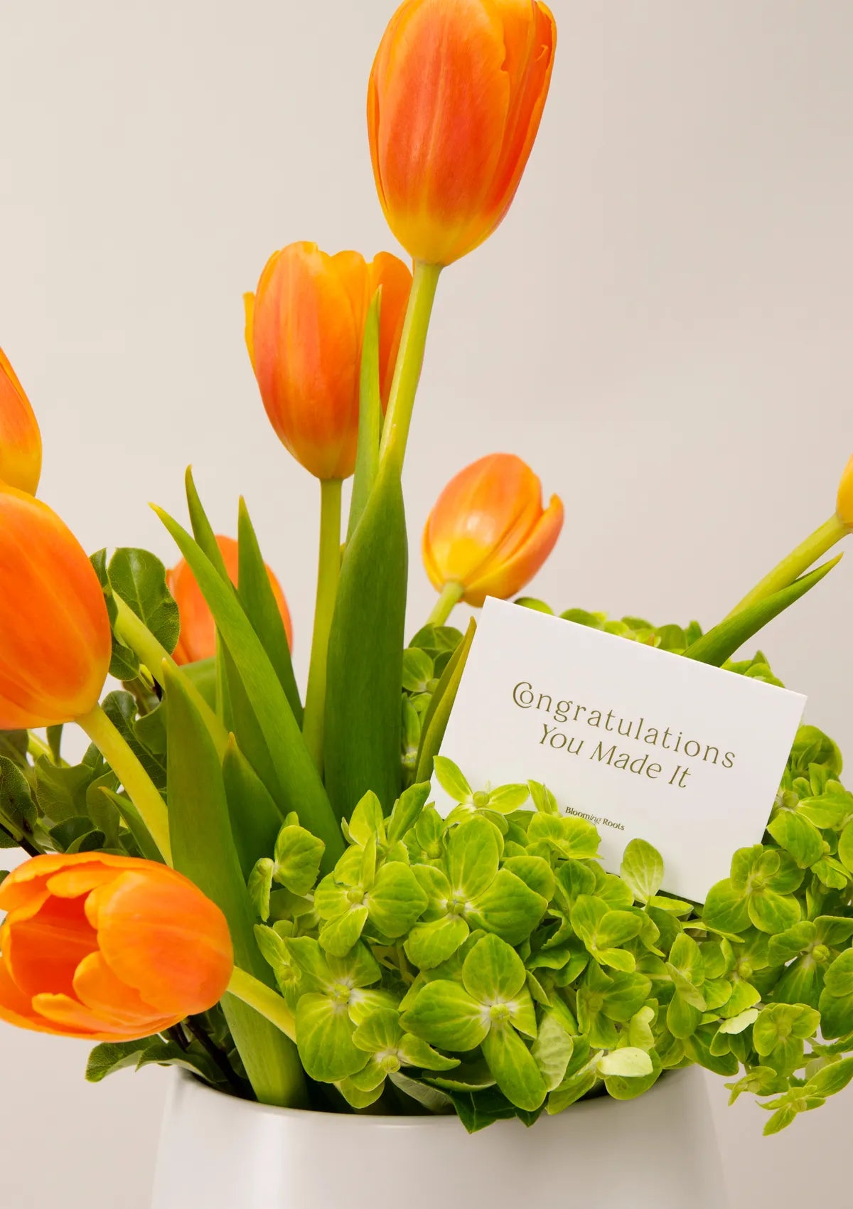 White Ceramic Lolanda Vase by Blooming Roots with a greeting card that has a logo on it.